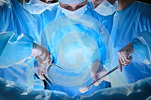 Group of surgeons at work in operating theater toned in blue