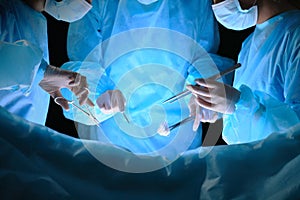 Group of surgeons at work in operating theater toned in blue