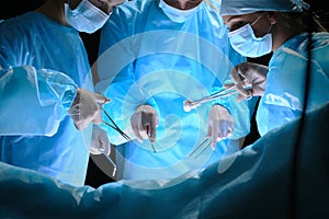 Group of surgeons at work in operating theater toned in blue