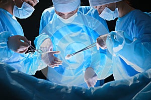 Group of surgeons at work in operating theater toned in blue