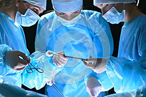 Group of surgeons at work in operating theater toned in blue