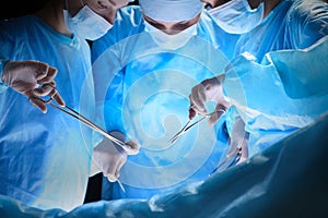 Group of surgeons at work in operating theater toned in blue