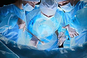 Group of surgeons at work in operating theater toned in blue