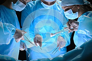 Group of surgeons at work in operating theater toned in blue