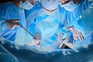 Group of surgeons at work in operating theater toned in blue