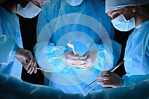 Group of surgeons at work in operating theater toned in blue