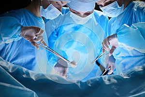 Group of surgeons at work in operating theater toned in blue