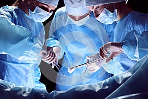 Group of surgeons at work in operating theater toned in blue