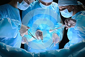 Group of surgeons at work in operating theater toned in blue