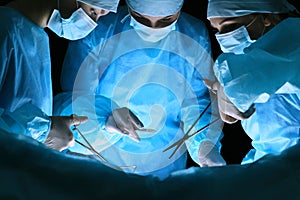 Group of surgeons at work in operating theater toned in blue