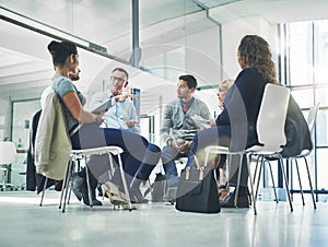 Group of talking business professionals sitting together in a circle for a team meeting. A bunch of design employees and