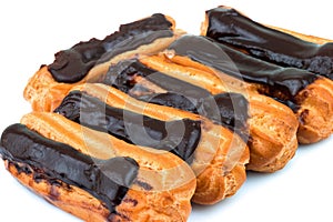 Group of tasty eclairs with custard and chocolate icing on white background. Sweet pastry products