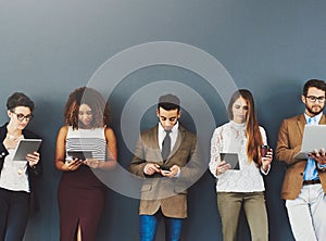 Group or team of business people working and browsing with wireless technology in studio against a grey background