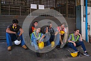 Group of technician or workers sit in front of the door of factory and end of work and they look sad