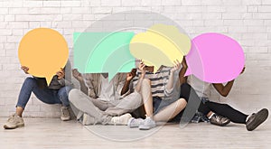 Group of teen friends covering faces with colorful speech bubbles