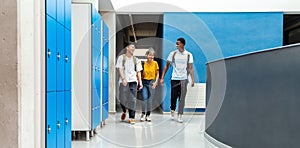 Group of teen high school students laughing walking in school corridor. Horizontal banner image. Copy space