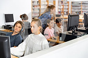 Group of teenage boys and girls learning to use computers in classroom