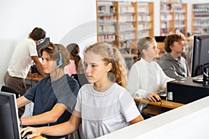 Group of teenage boys and girls learning to use computers in classroom