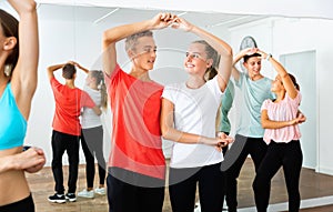 Group of teenage boys and girls training movements of slow foxtrot in dance studio with female coach