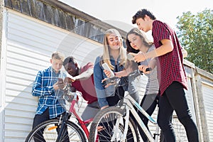 Group Of Teenage Friends On Bikes Looking At Mobile Phones