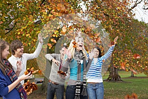 Group Of Teenage Friends Throwing Leaves In Autumn