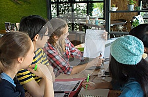 Group of teenage friends working and meeting in team with reports