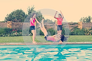 Group of 3 teenage girlfriends having fun in swimming pool. Play throwing each other in the pool