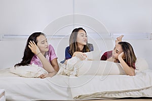 Group of teenage girls confiding together on bed