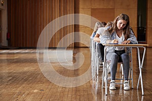 Group Of Teenage Students Sitting Examination In School Hall