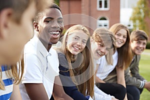 Group Of Teenage Students Sitting Outside School Buildings photo