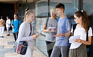 Group of teenager students resting in schoolyard during recess