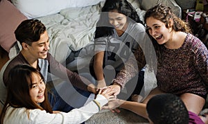 Group of teenagers in a bedroom putting their hands together community and teamwork concept