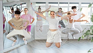 Group of teenagers dancing and jumping in dance studio during class