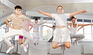 Group of teenagers dancing and jumping in dance studio during class