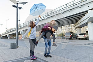 Group of teenagers friends having fun in the city, laughing kids with umbrella. Urban teen lifestyle