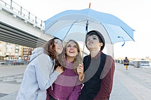 Group of teenagers friends having fun in the city, laughing kids with umbrella. Urban teen lifestyle