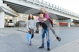 Group of teenagers friends having fun in the city, laughing kids with umbrella. Urban teen lifestyle