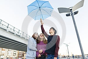 Group of teenagers friends having fun in the city, laughing kids with umbrella. Urban teen lifestyle