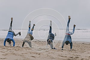 Friends Doing Handstands On A Winter Beach