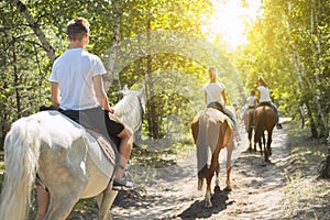 Group of teenagers on horseback riding in summer park