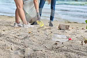 Group of teenagers on riverbank picking up plastic trash in bags