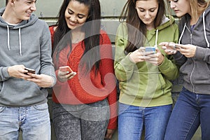 Group Of Teenagers Sharing Text Message On Mobile Phones