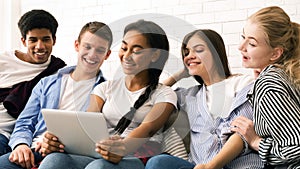Group of Teenagers Sitting on Couch Looking at a Tablet