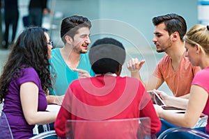 A group of teenagers sitting at the table in cafe, using laptop and drinking orange juice.