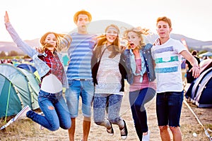 Skupina teenagerů na letním hudebním festivalu, skákání