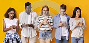 Group of teenagers using mobile phones over yellow background