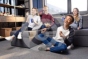 Group of teenagers watching movie together at home, teenagers having fun concept