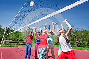 Group of teens with arms up play volleyball