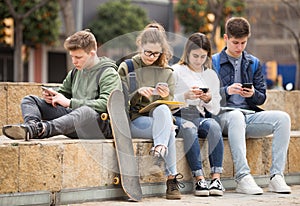 Group of teens using smartphones outdoors