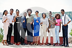 Group of ten african american people posed at street of city. Fashionable people of Africa shows thumb up